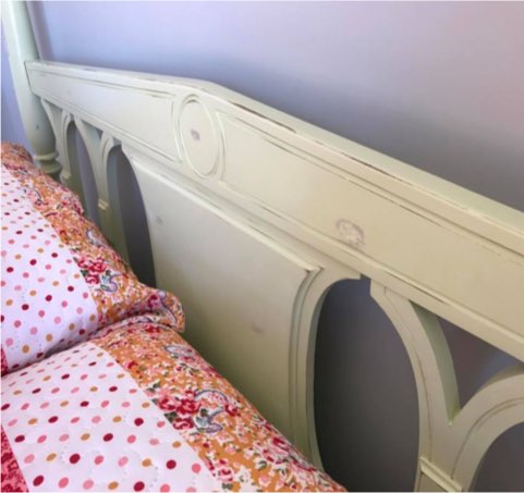 Pale green painted wooden bed head with floral bedding